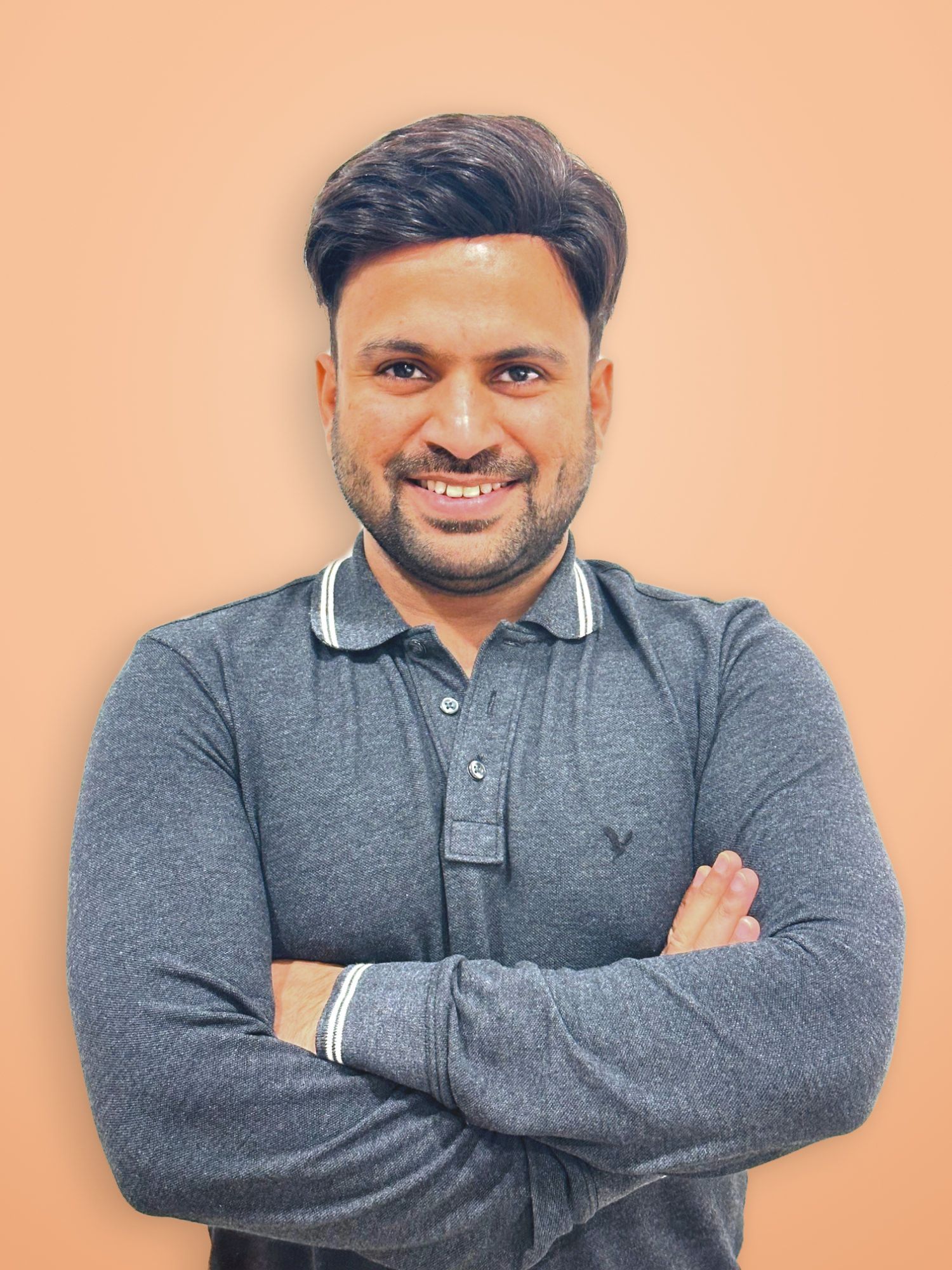 Amandeep smiling with his arms folded, in a grey polo shirt
